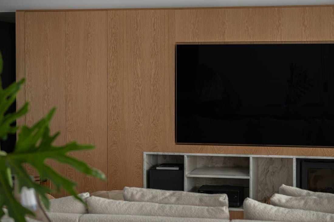 Muro de televisor revestido en paneles de roble con mueble bajo abierto