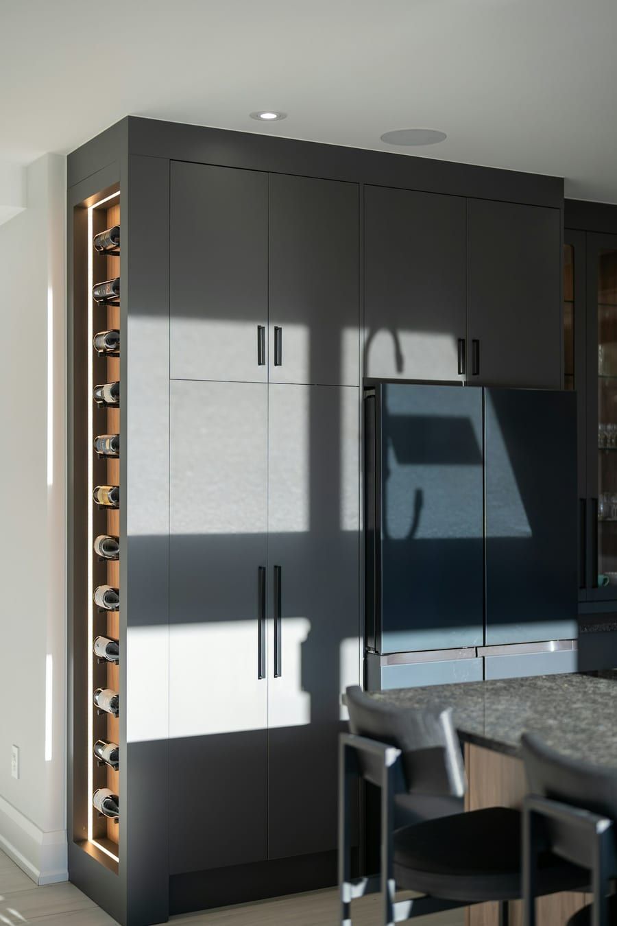 Cocina integral gris con gabinetes hasta el techo y cava vertical para vinos iluminada con LED